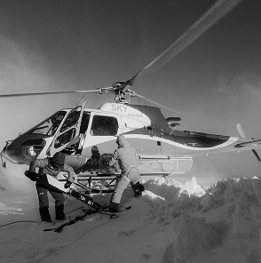 an helicopter landing on the top of a peak in the alps unloading filming gear