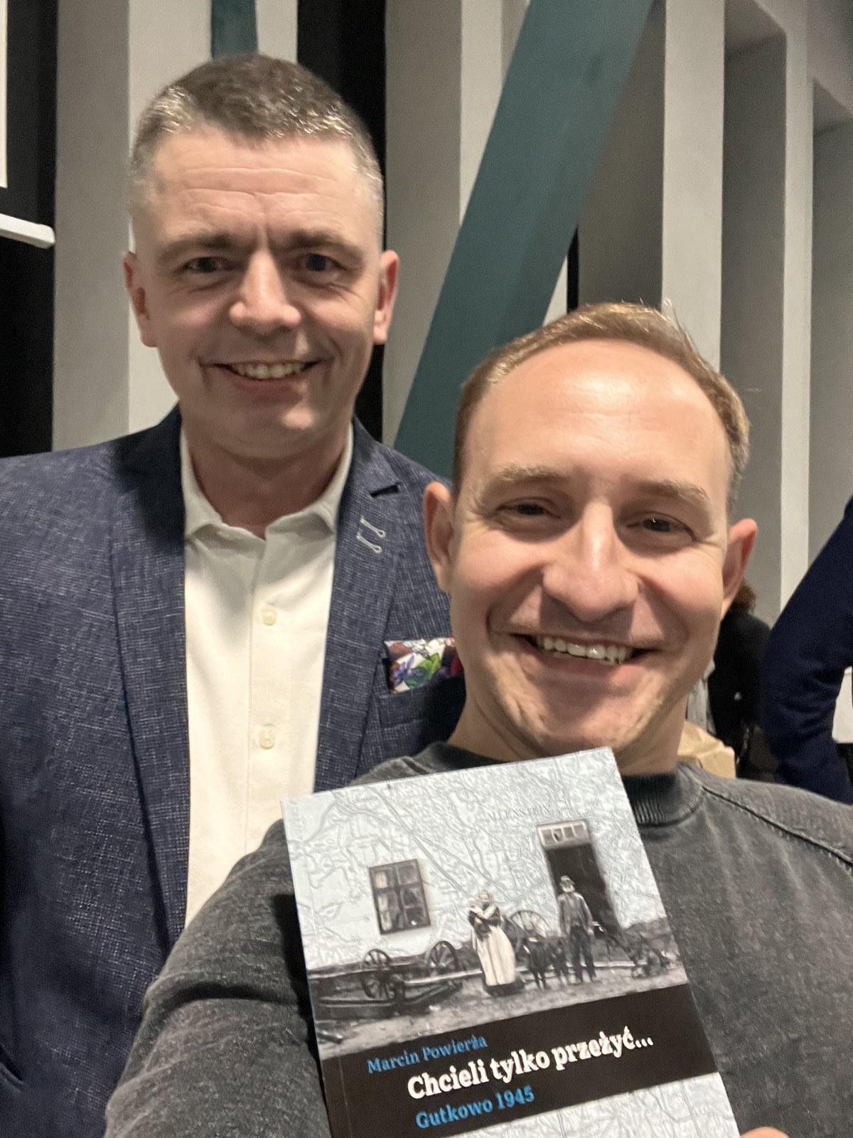 Aleks from Slovlog standing with author Marcin Powierza after the book talk, holding his signed copy