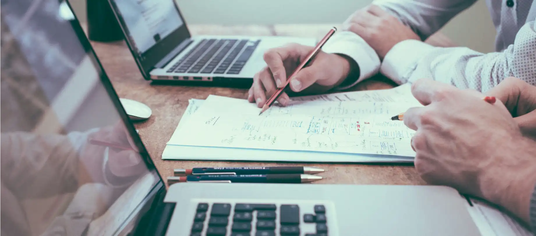 photo gros plan de mains, ordinateurs et cahier de notes