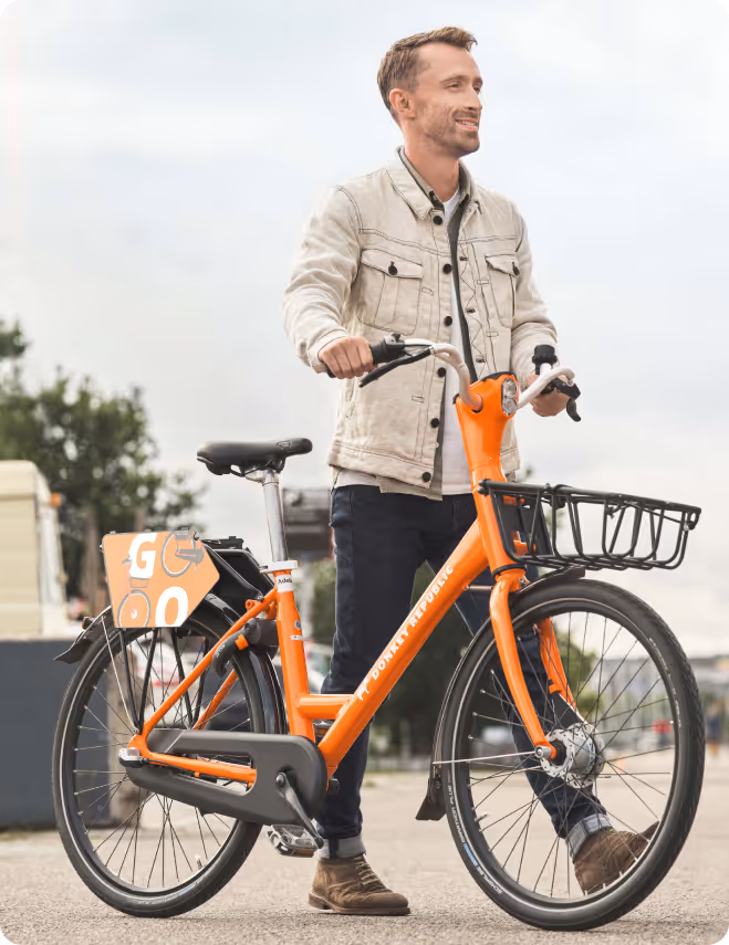 A man standing next to an orange bike.