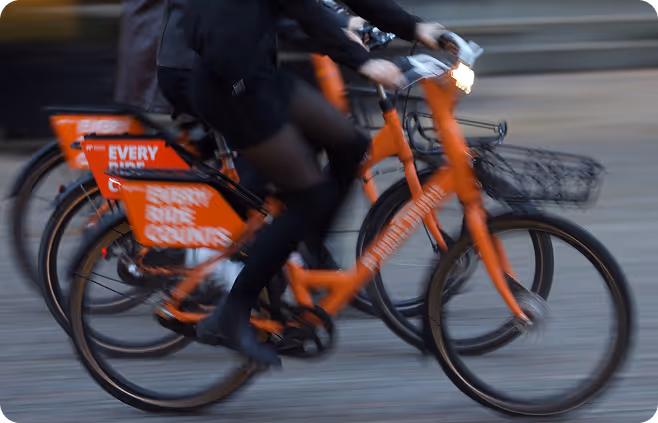 A man riding a bike down a street next to another man.