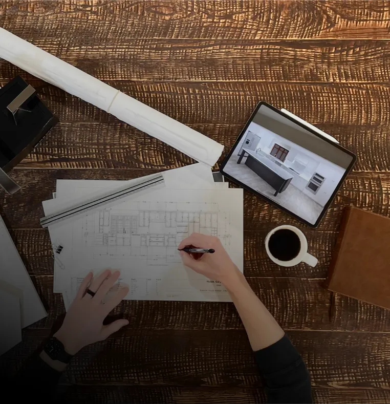 hand working on blueprints with tablet and coffee beside