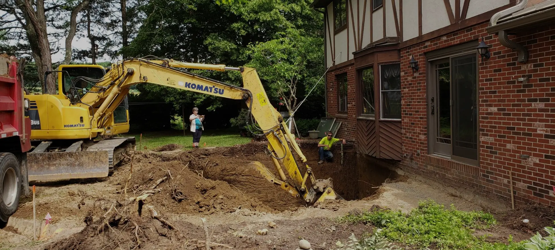 excavator digging in front of house