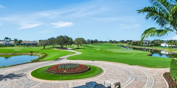Scenic golf course with green fairways, water hazards, palm trees, and a circular flower bed surrounded by paved paths.