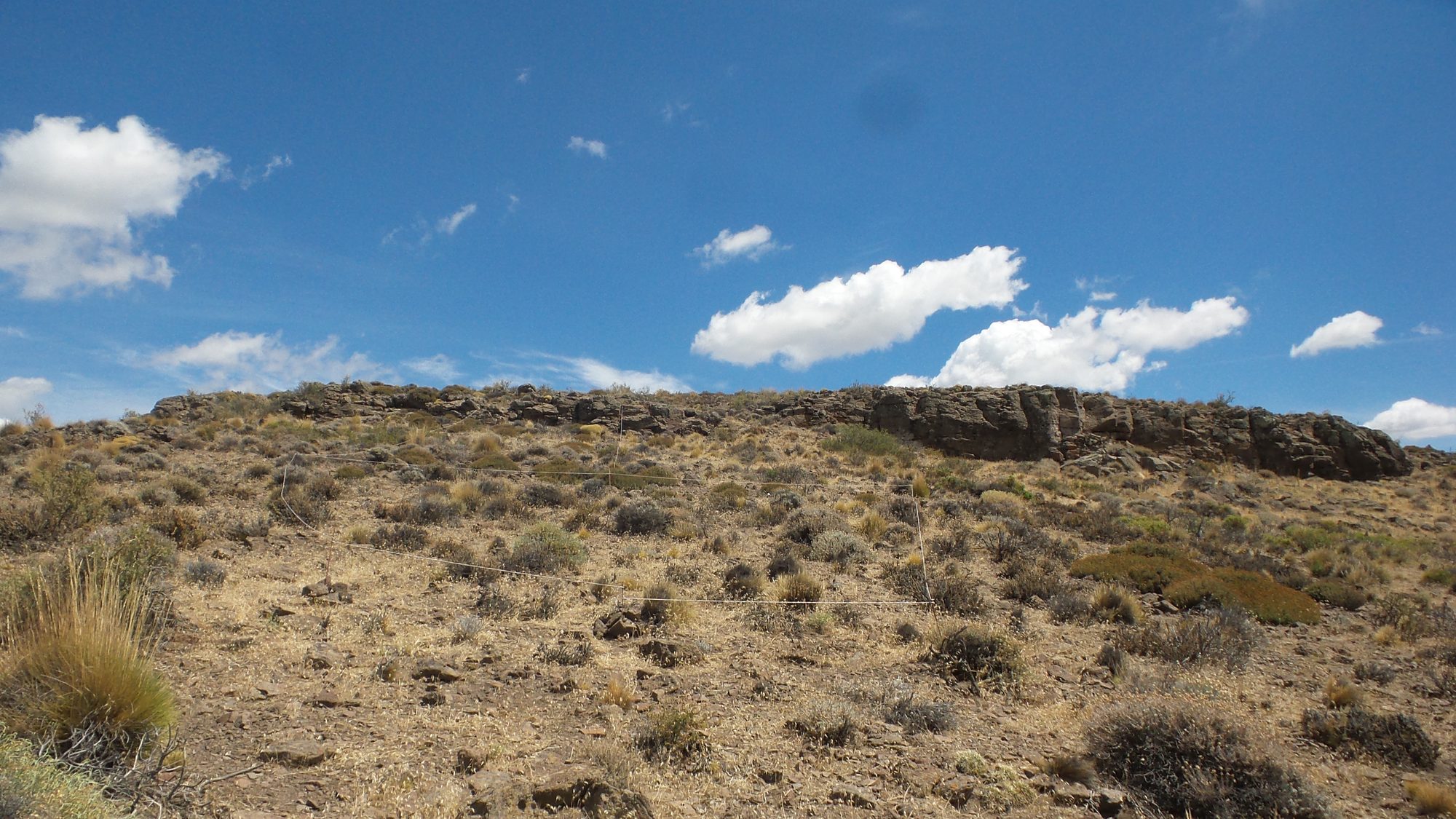 Cerro basáltico bajo cielo azul con nubes