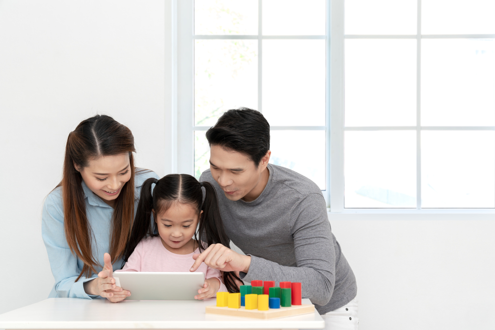 Happy people watching or playing digital tablet, laptop or mobile with cheerful expressions at desk.