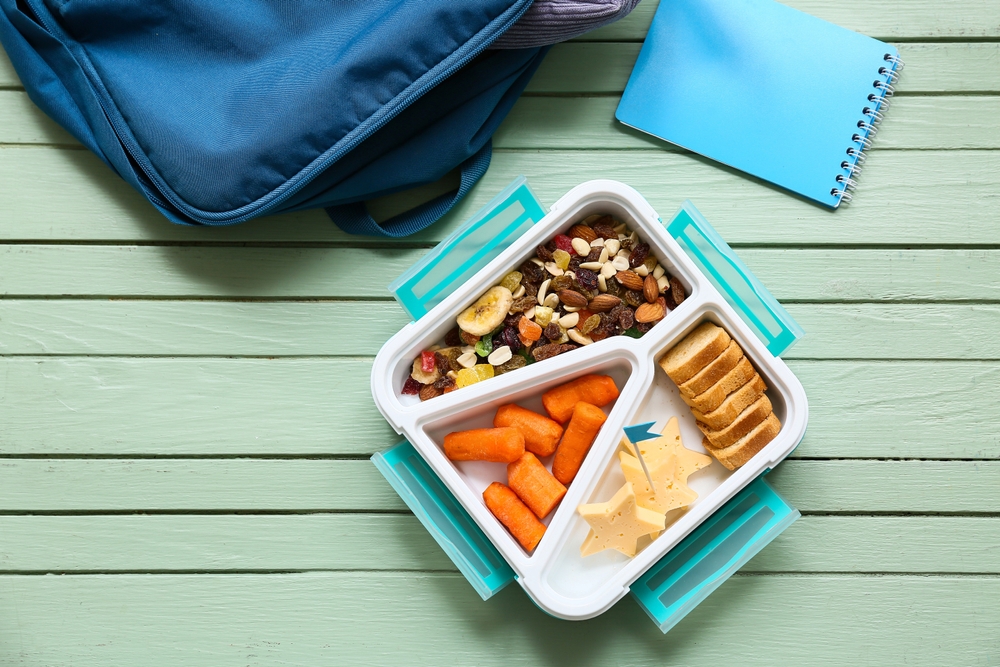 Lunch of nutritional variety alongside school backpack on green wooden background