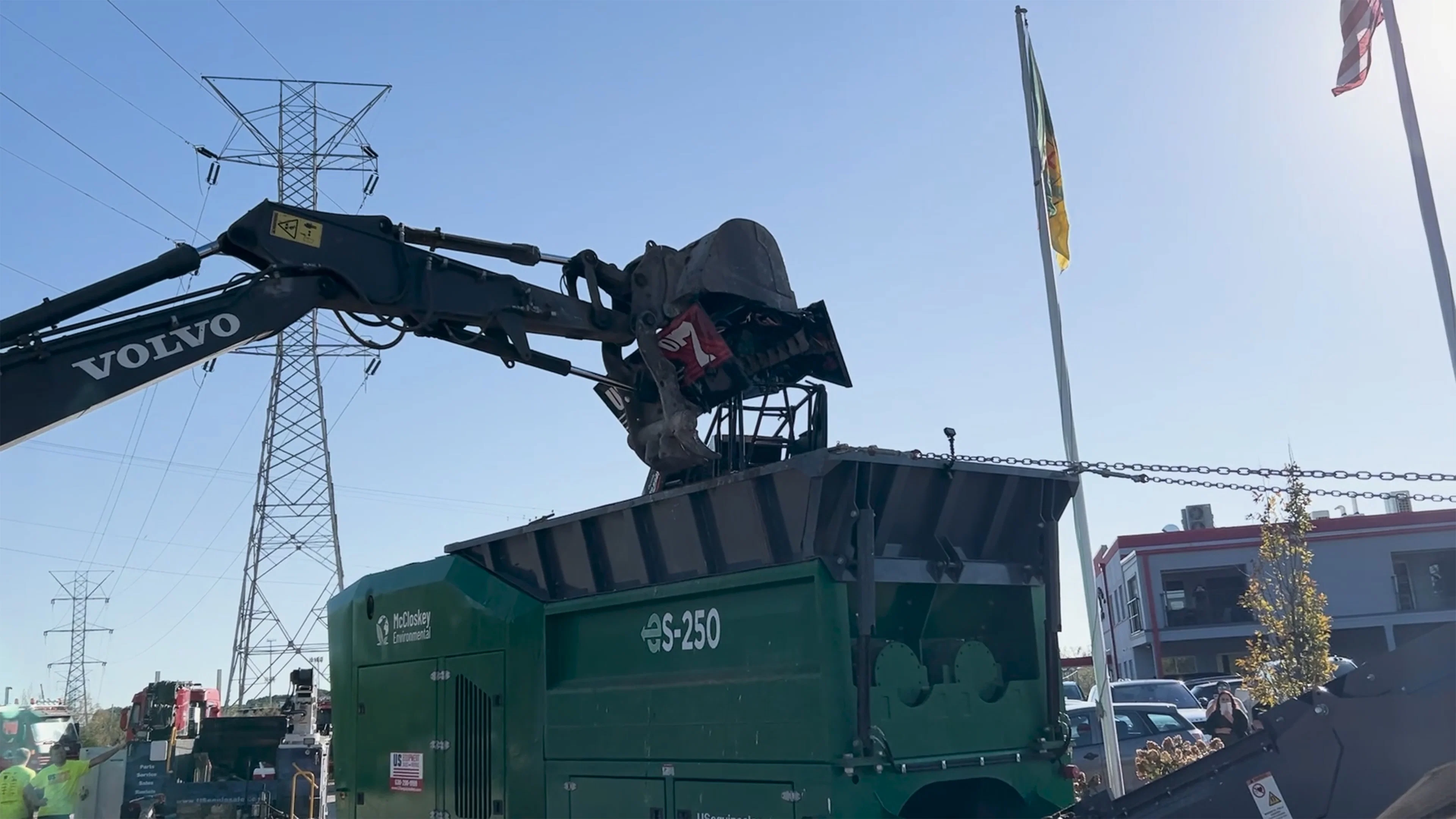Volvo excavator loading material into a McCloskey Environmental S-250 screener during active recycling operations, demonstrating high-capacity screening equipment performance.