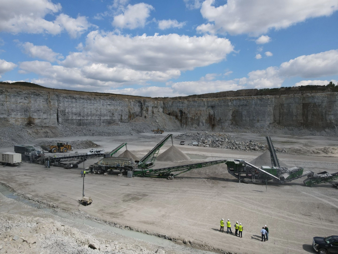 Full crushing and screening plant operating in a limestone quarry with conveyors stockpiling processed aggregate material.