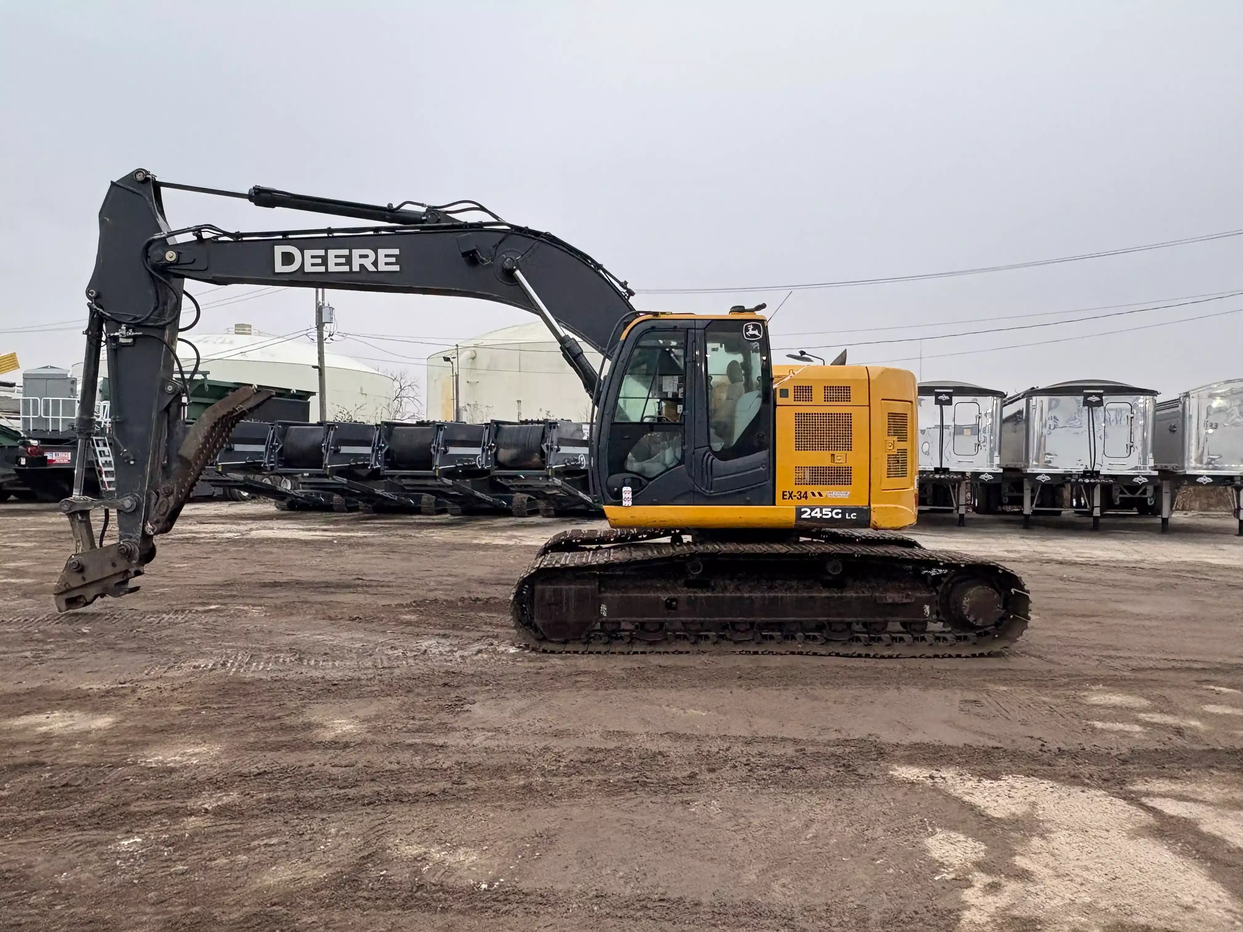 John Deere tracked excavator parked in an equipment yard, configured for heavy excavation and material handling applications.