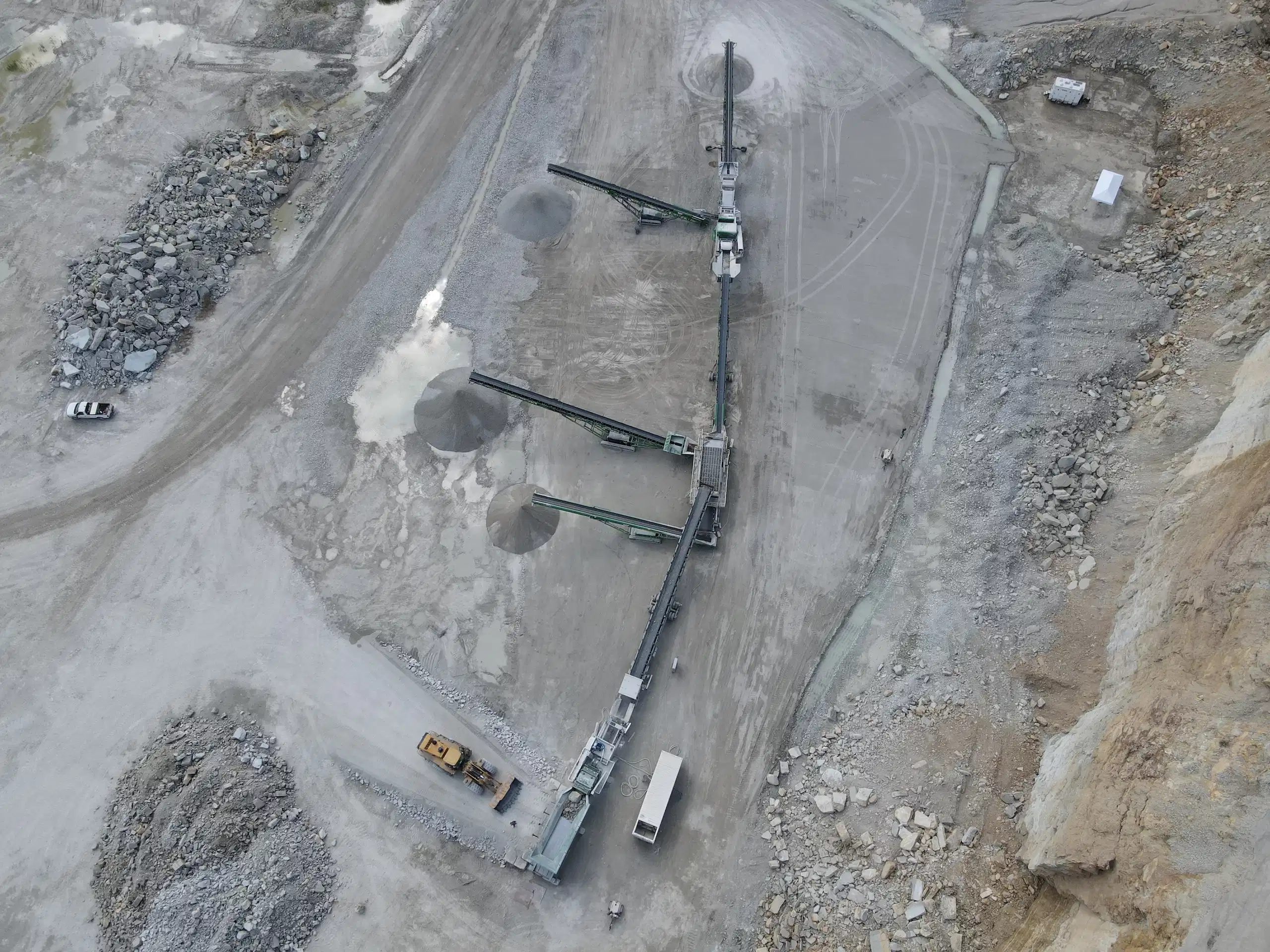 Drone view of a full conveyor spread in a quarry, showing multiple stackers producing aggregate stockpiles and feeding material through a complete crushing setup.