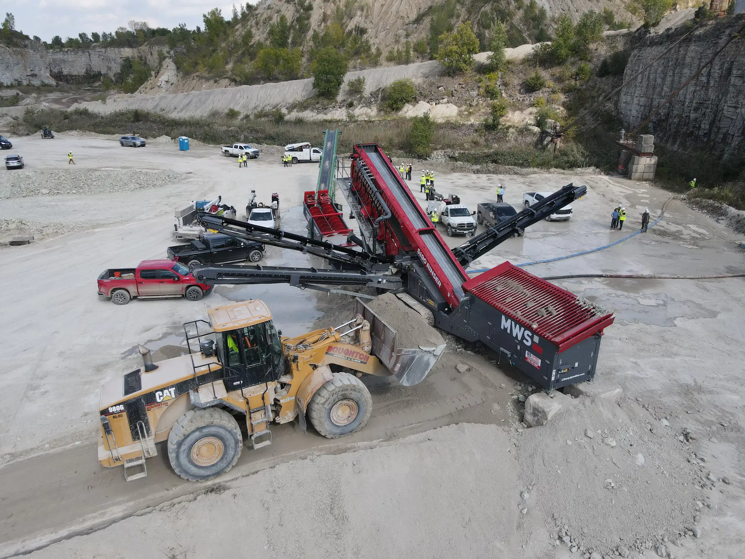 MWS modular wash plant operating in a quarry as a CAT wheel loader feeds material into the hopper, with conveyors and screening components processing sand and aggregate.