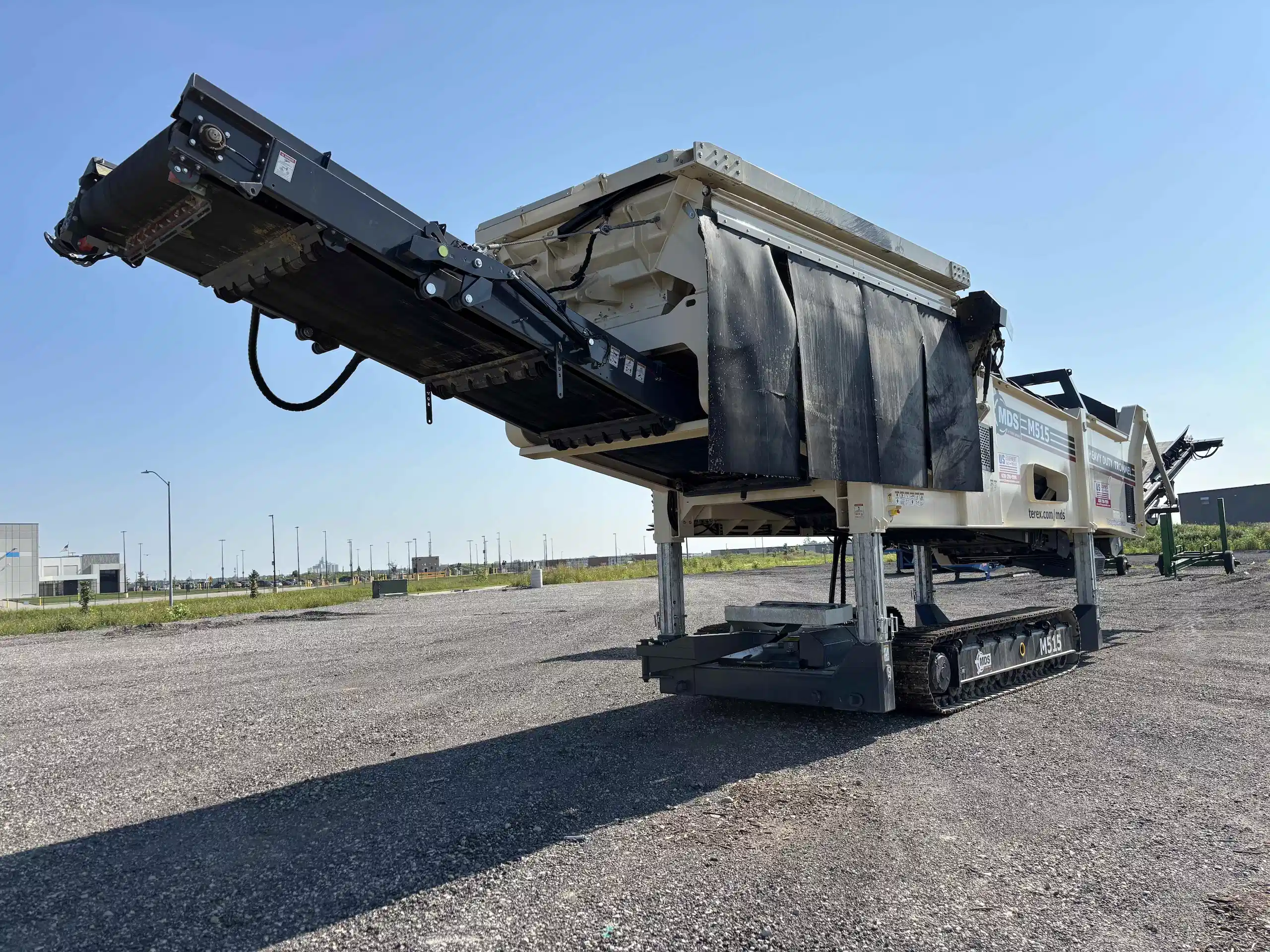 MDS M515 tracked trommel showing rear discharge conveyor and screening drum at an equipment yard.