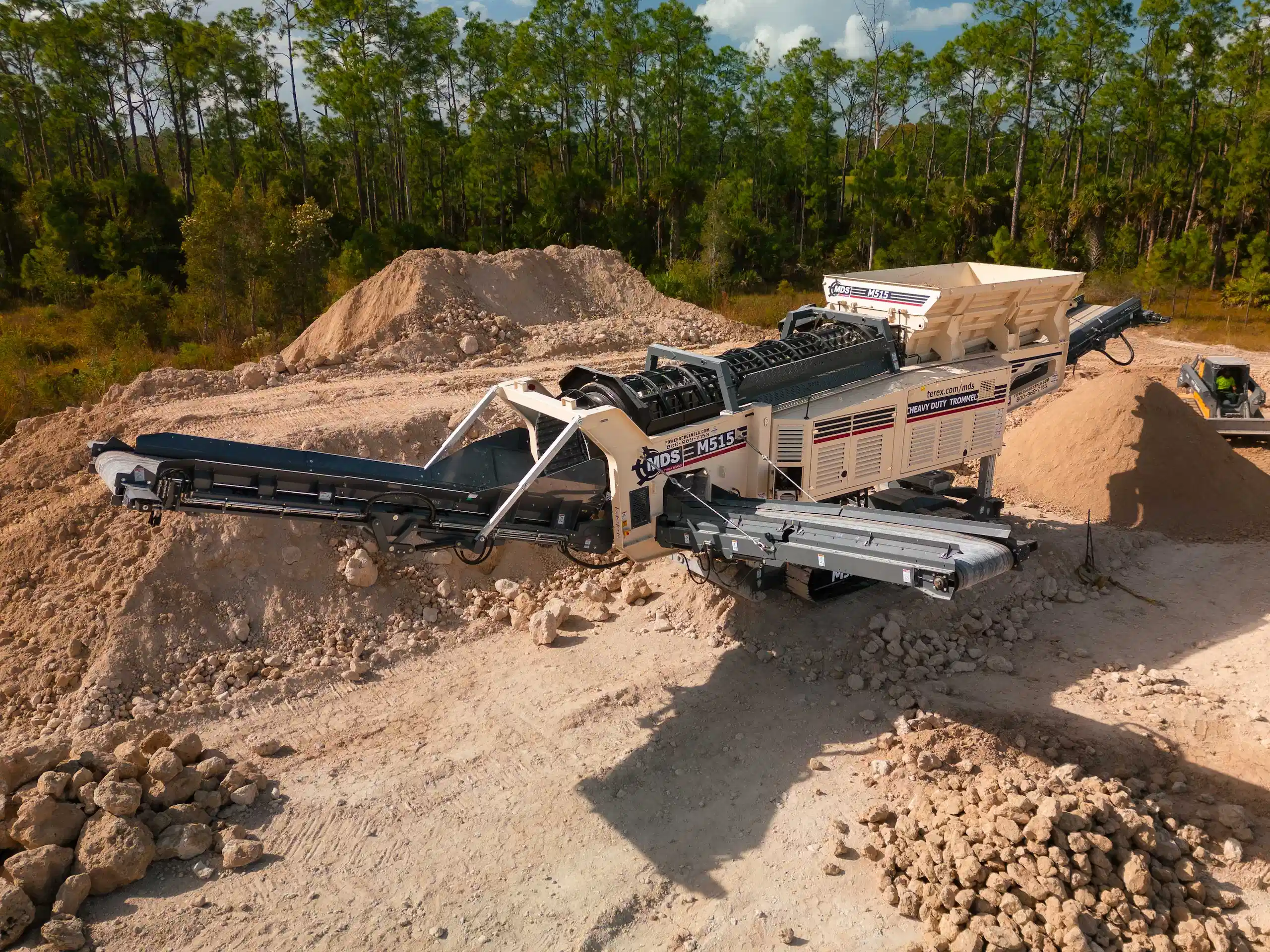 MDS M515 track trommel screening aggregate material in a quarry environment with stockpiles and conveyors.