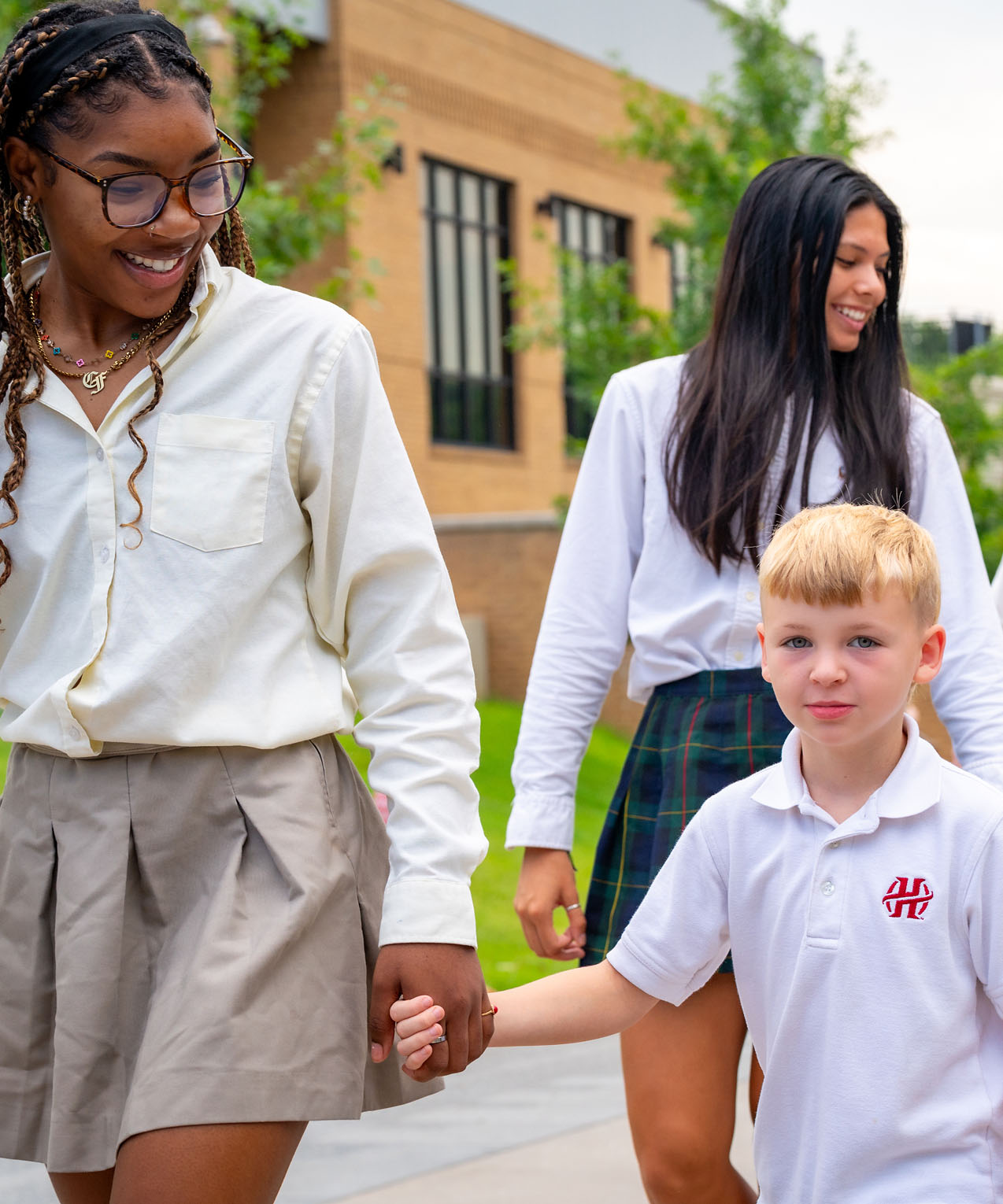 Older students walking with a young student.