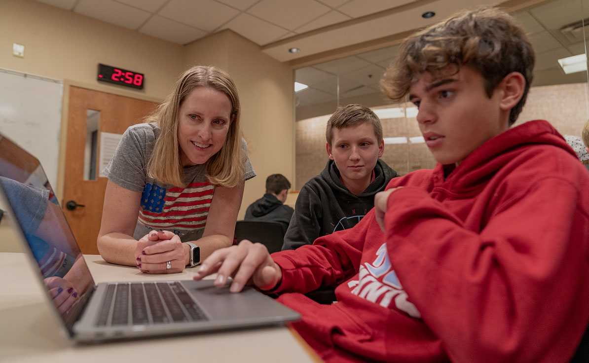 A staff member helping student with his computer.