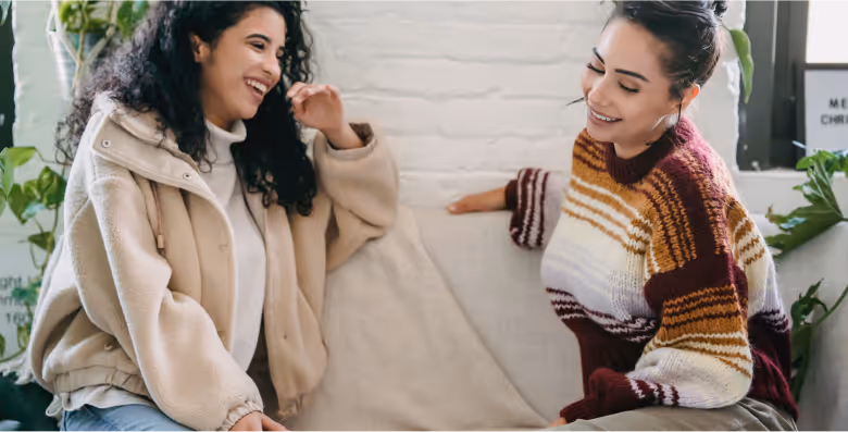 Two women chatting and smiling on a sofa