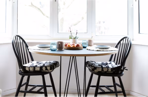 Photo of a dining table and two chairs next to a bright window