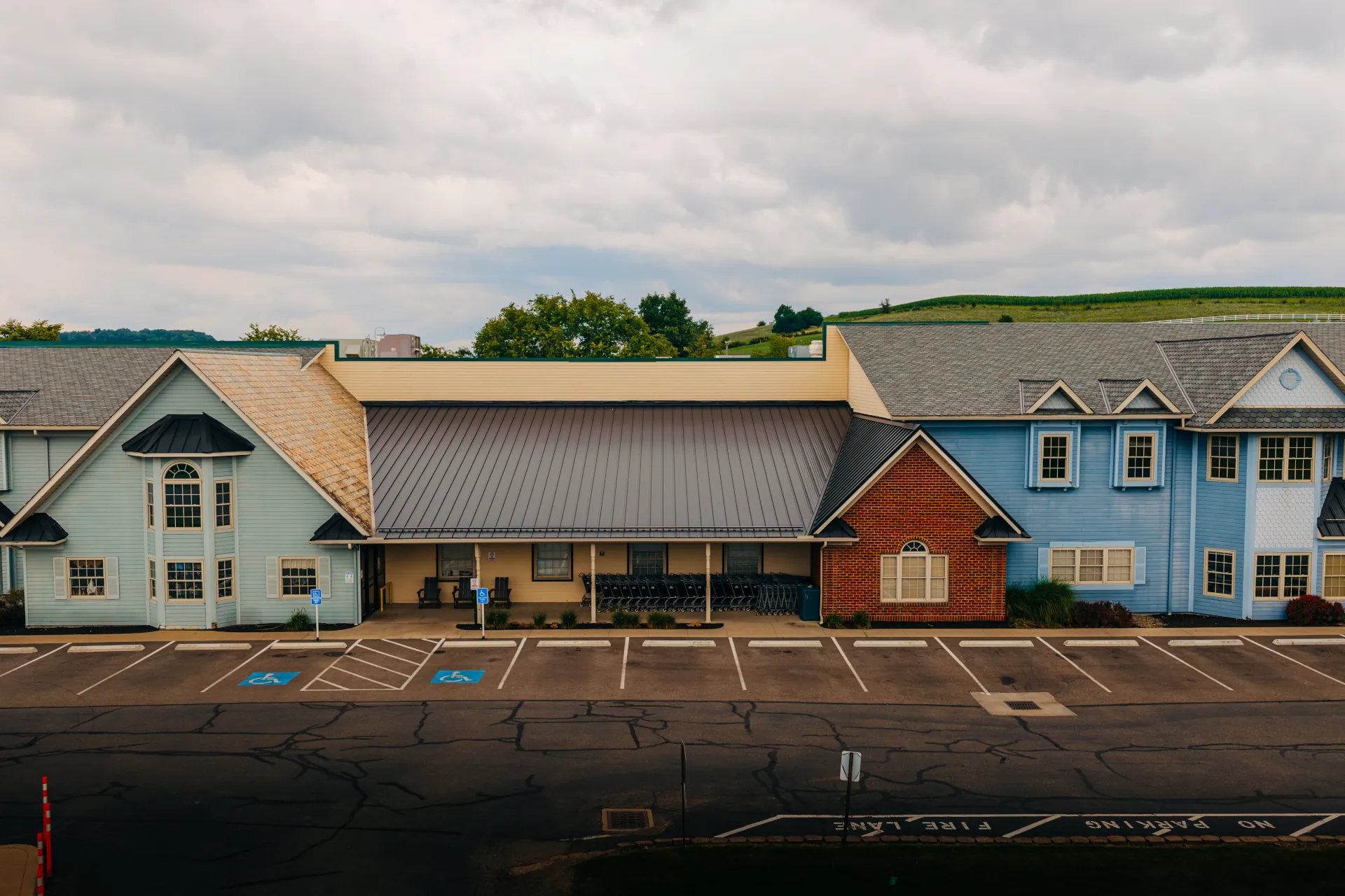 Dark standing seam metal roof over the entrance to Walnut Creek Cheese, with blue storefront buildings on either side.