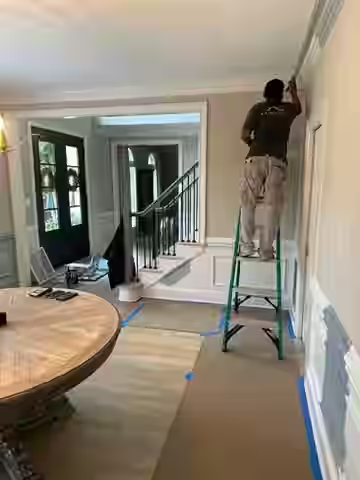 painters carefully covering furniture and floors with plastic sheeting and drop cloths - Charlotte home painters