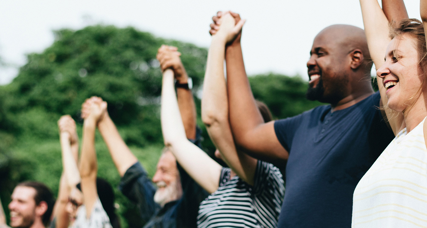 Diverse group of people holding hand up in the air