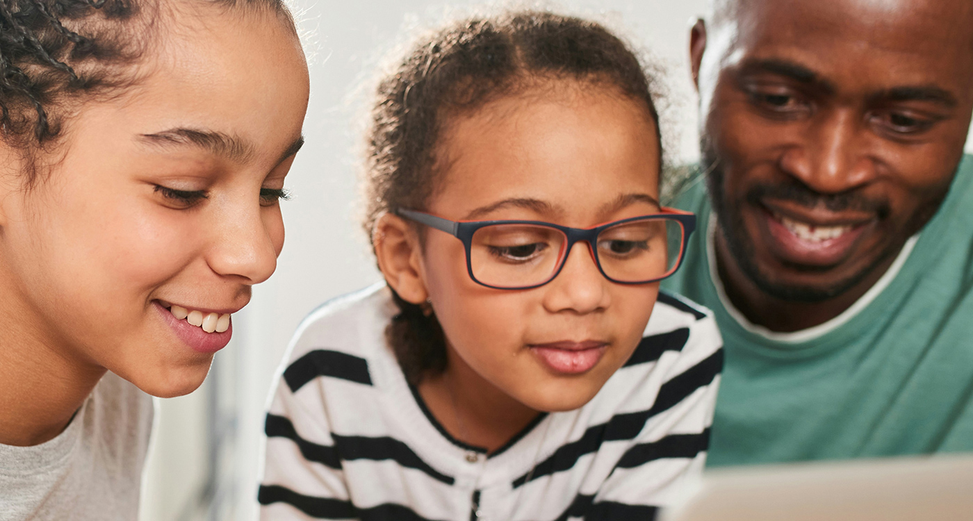 Father and 2 daughters looking at a device together