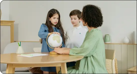 Teacher showing globe to two students at table