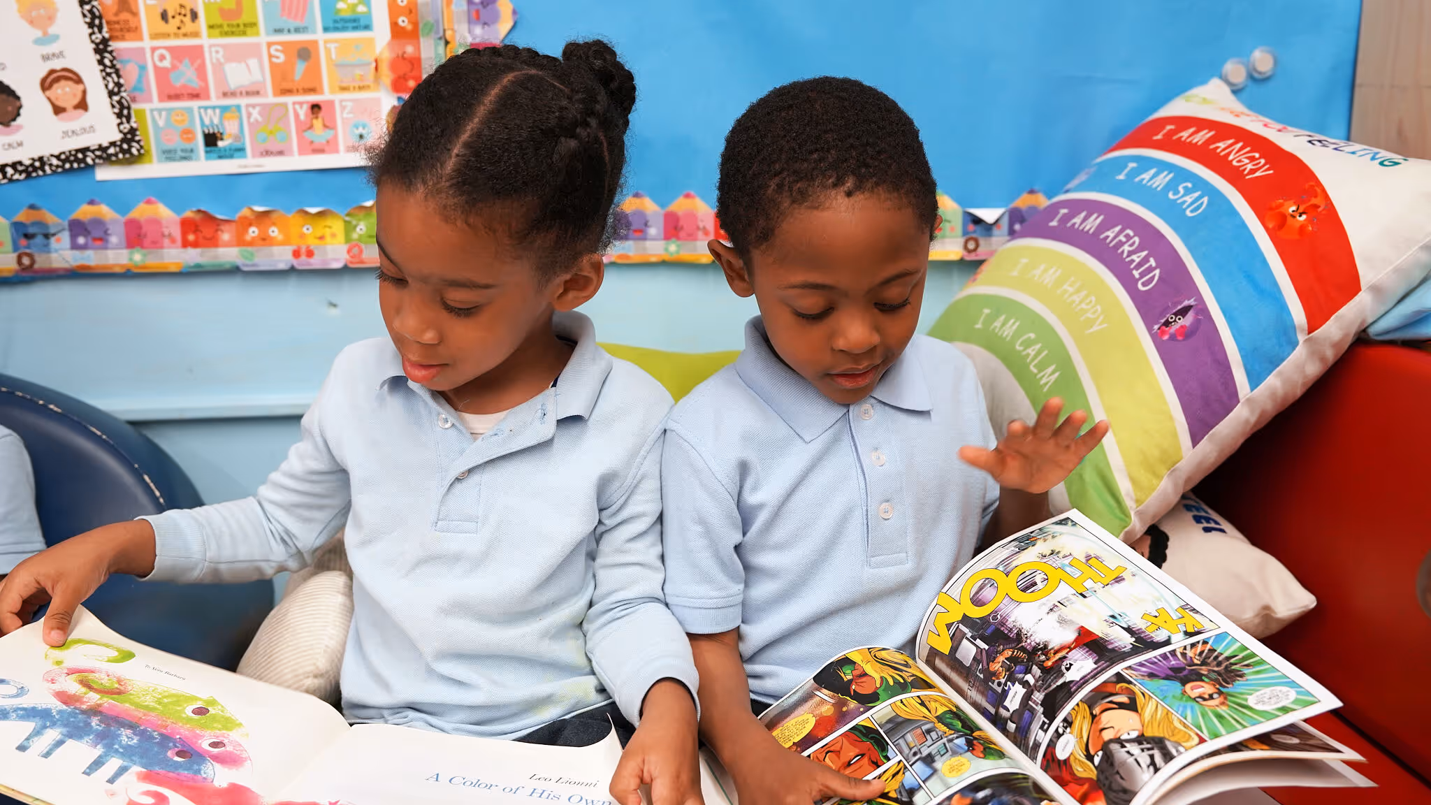 Large beige stone courthouse building with tall vertical windows and Art Deco architectural style, situated on a raised platform with a stone retaining wall. The entrance features tall columns and sculptural reliefs. Two flagpoles are visible, one with the American flag and one with the New York State flag. A few pedestrians and parked cars are present on the street below. The sky is clear and blue.
