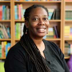 Loukisha Prince smiling in front of a library bookshelf