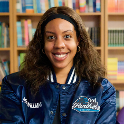 Adrienne Williams smiling in a Panthers jacket in a library