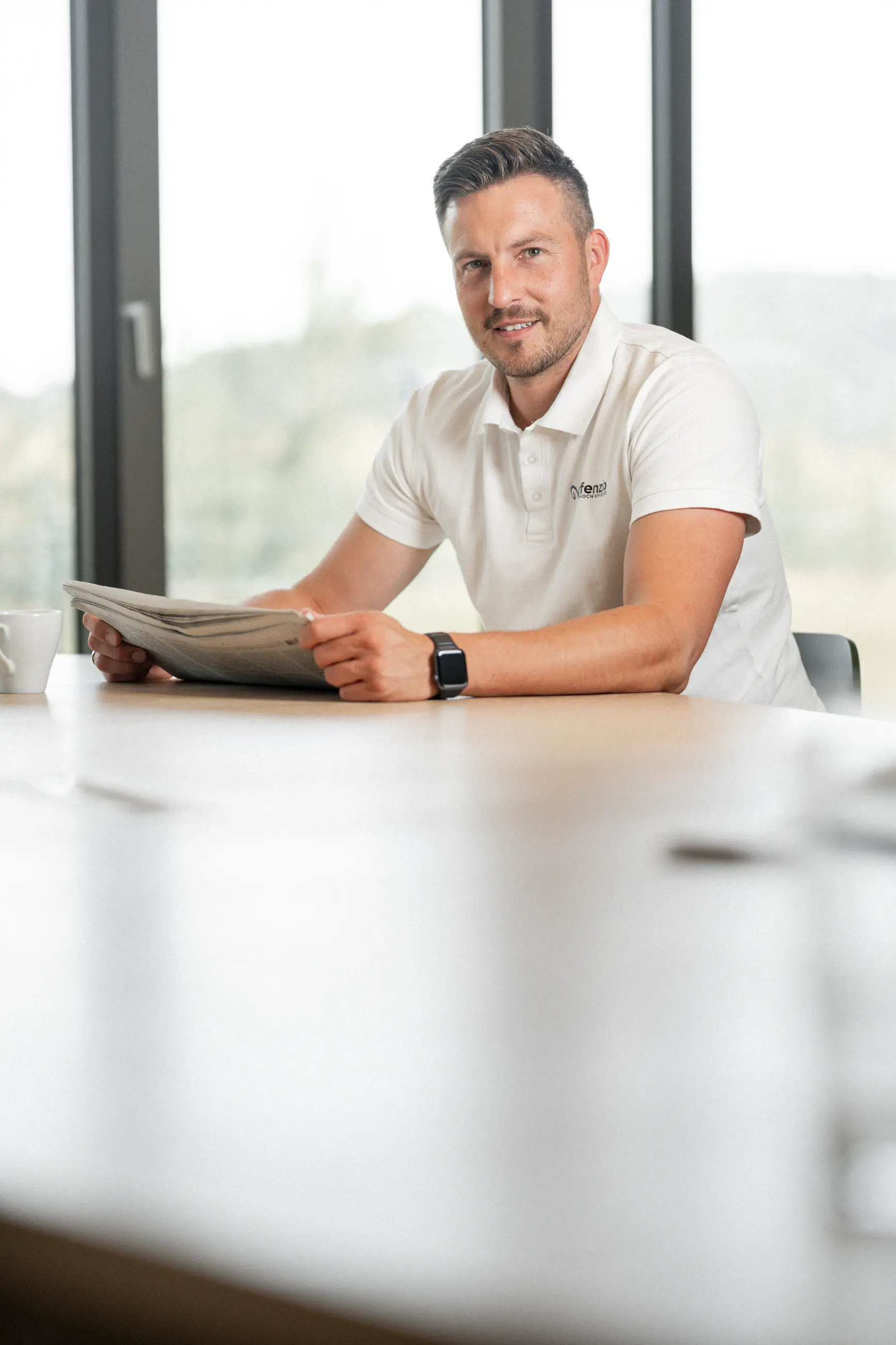Jan Lawall liest sitzend eine Zeitung und sieht in die Kamra