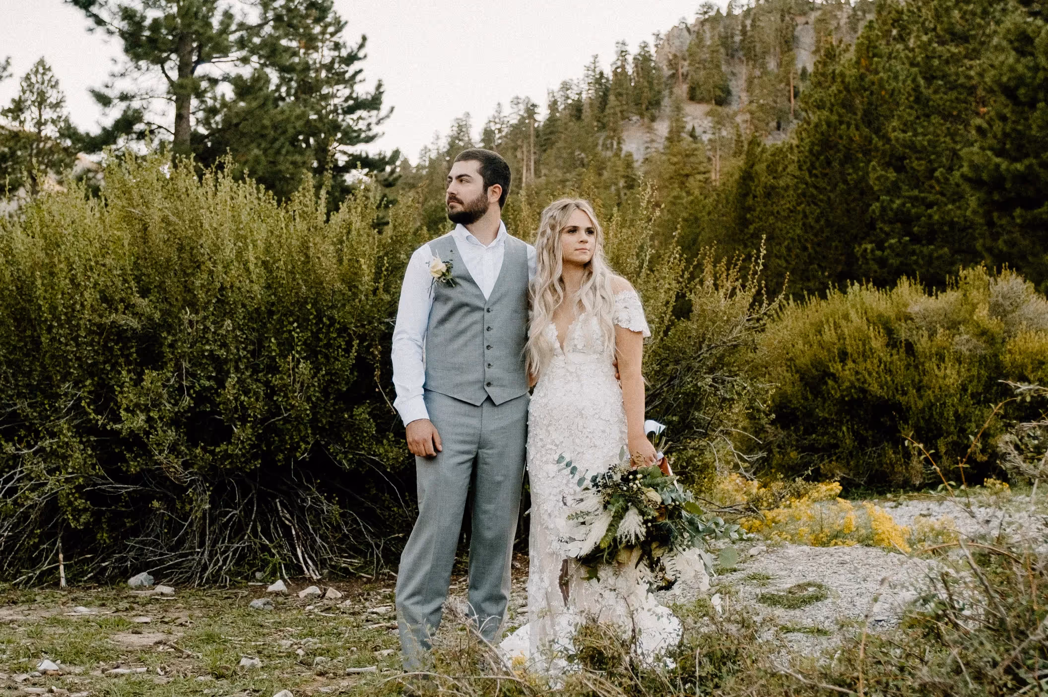 Layne and Tim's stress-free Mount Charleston wedding, couple posing in rustic chic attire surrounded by lush forest scenery near Las Vegas