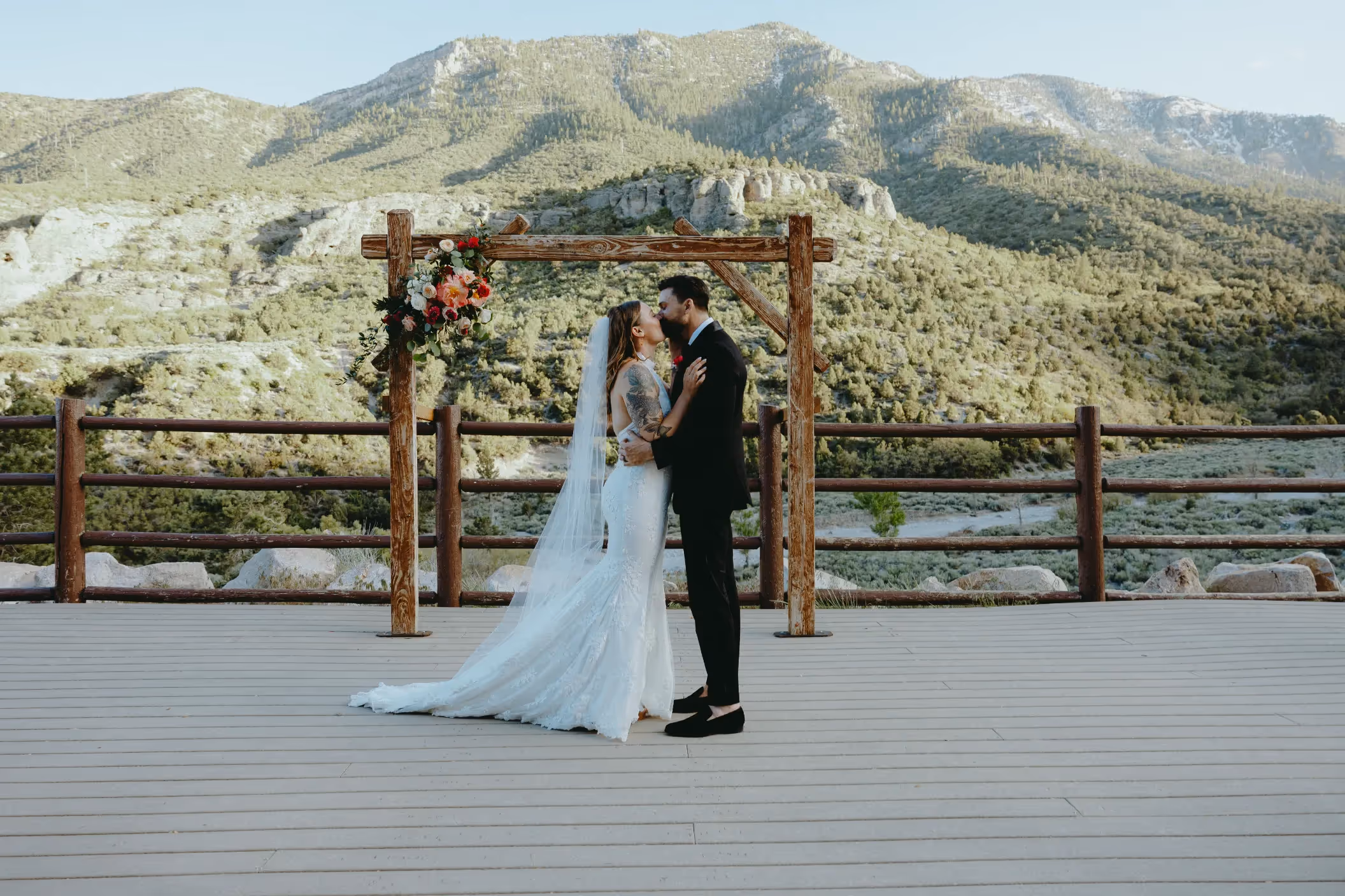 Abigail and Alex's rustic chic Mount Charleston wedding, couple sharing a tender moment under floral arch with panoramic mountain views near Las Vegas
