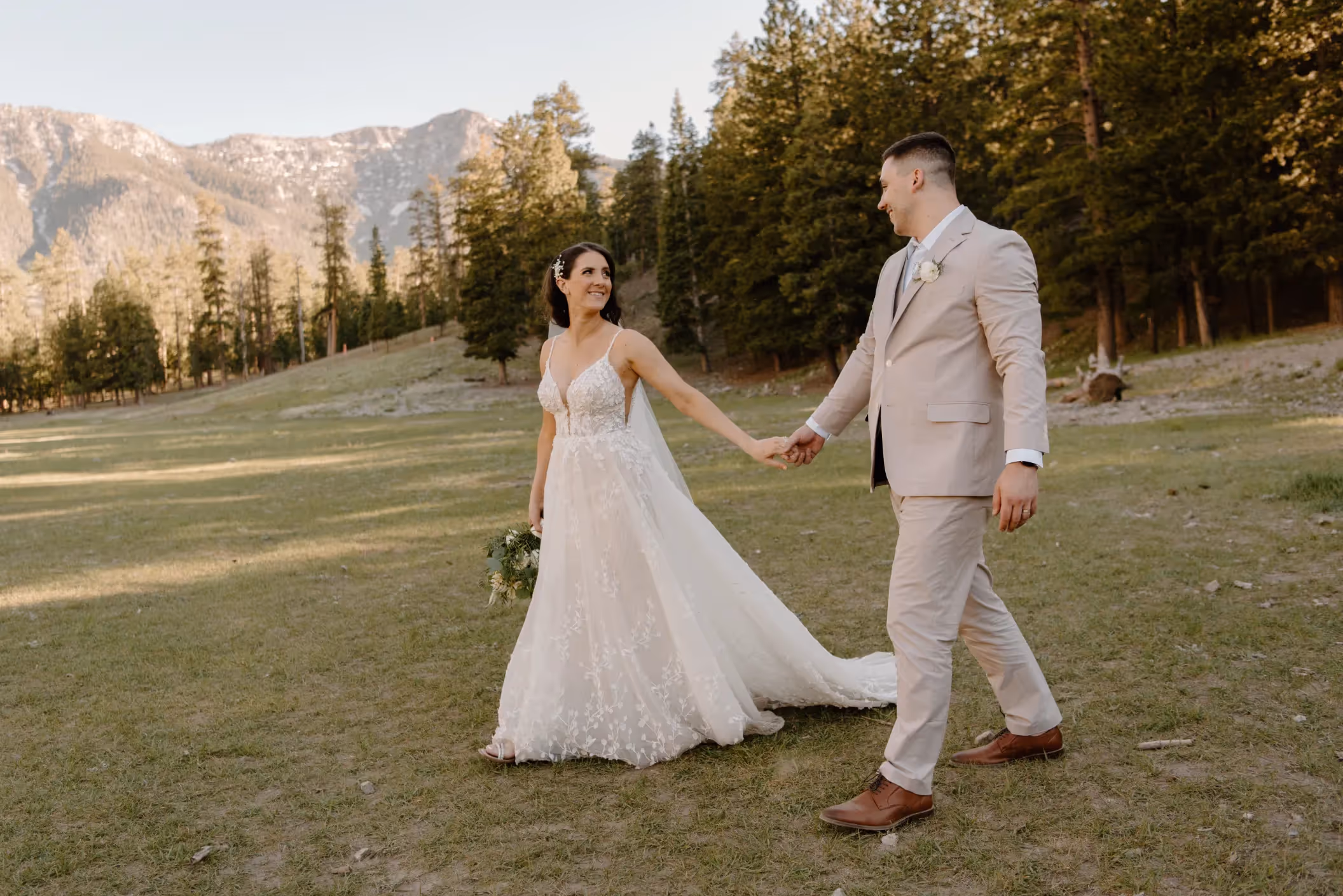 Ashley and Andrew's romantic Mount Charleston elopement, newlyweds walking hand-in-hand through scenic meadow with pine forests and mountains in Las Vegas