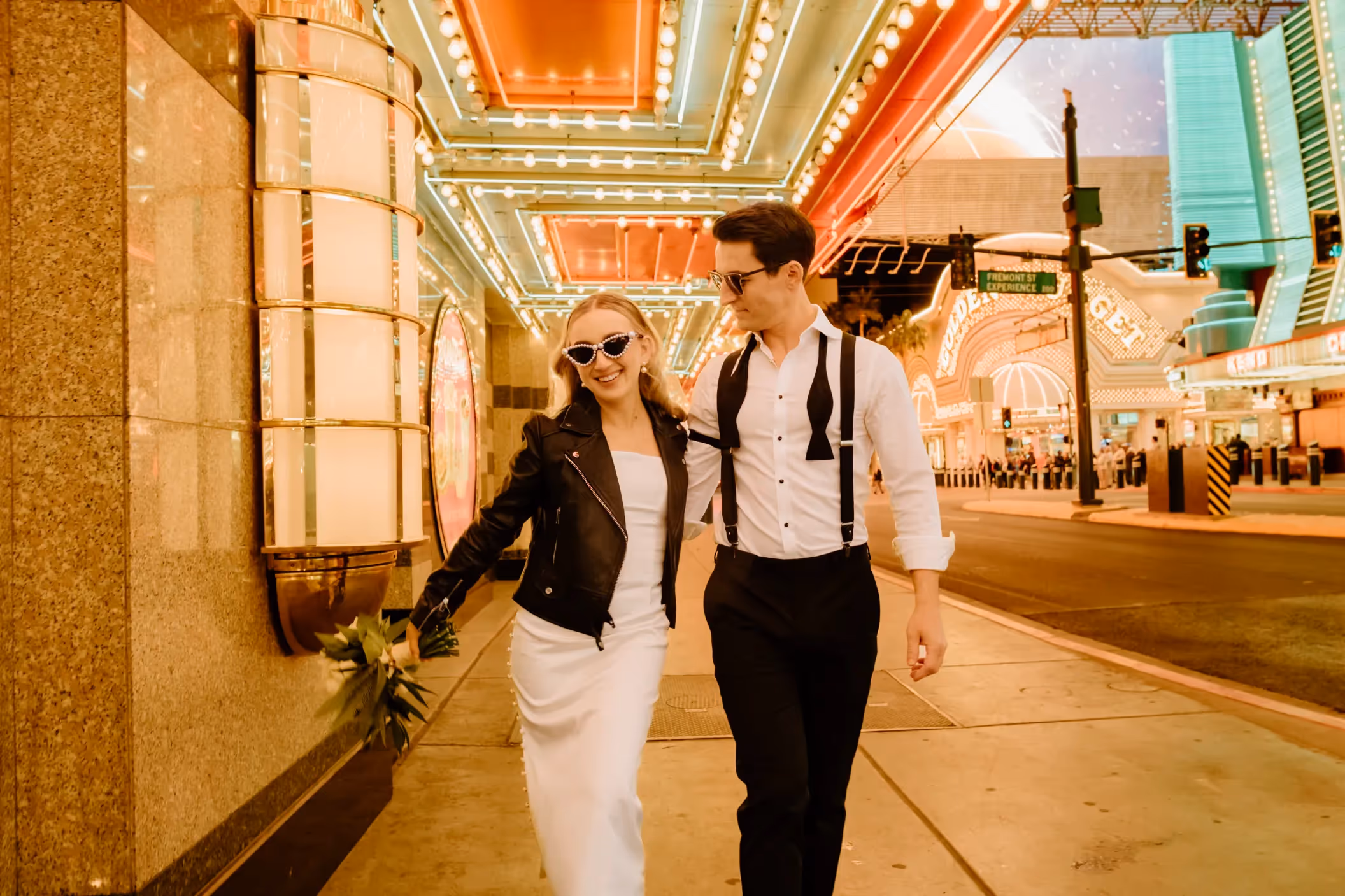 Paige and Lloyd's stylish Downtown Las Vegas elopement, couple strolling along illuminated Fremont Street Experience in edgy wedding attire