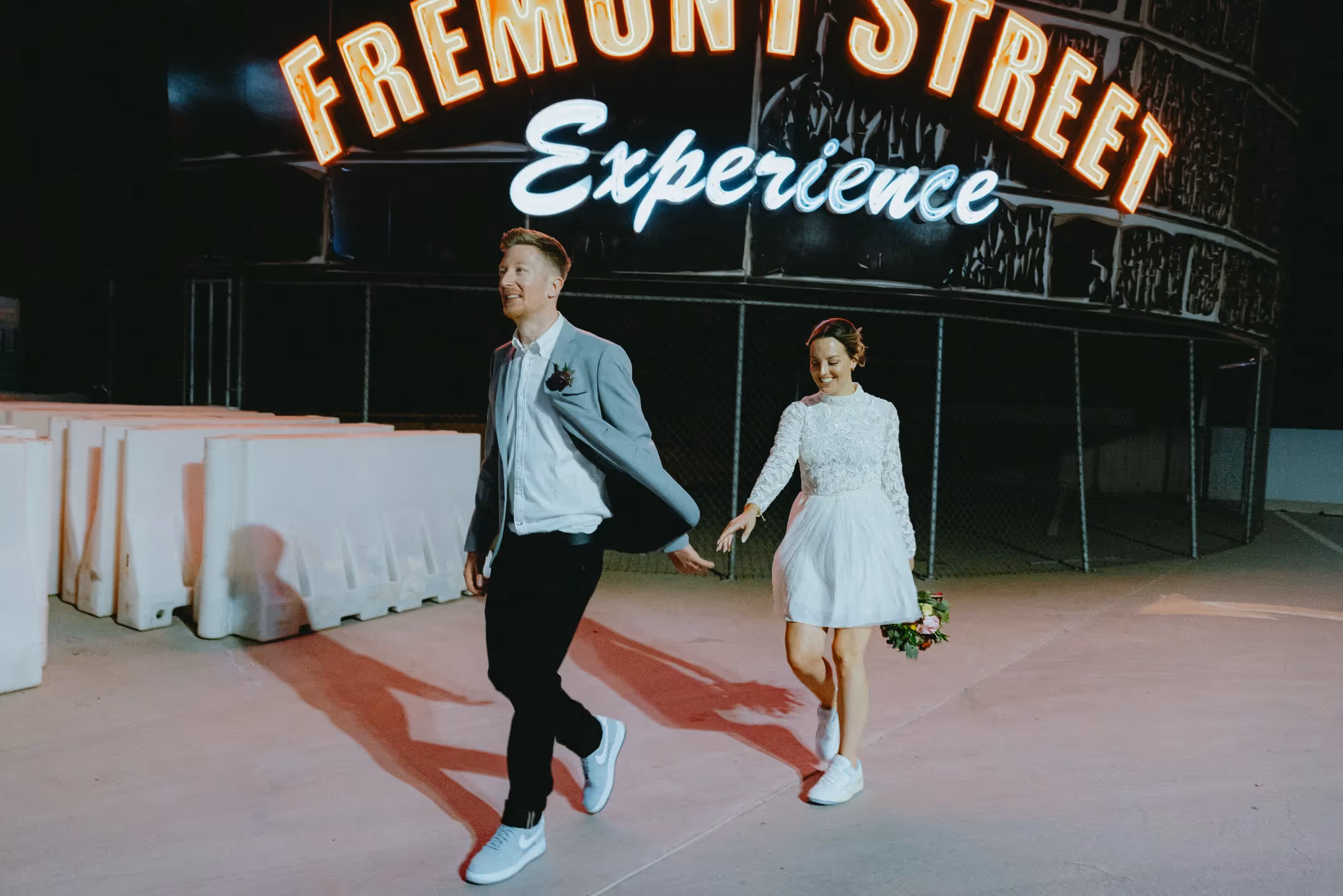 Charlot and Teash's unique Downtown Las Vegas elopement, joyful couple running hand-in-hand under the Fremont Street Experience sign