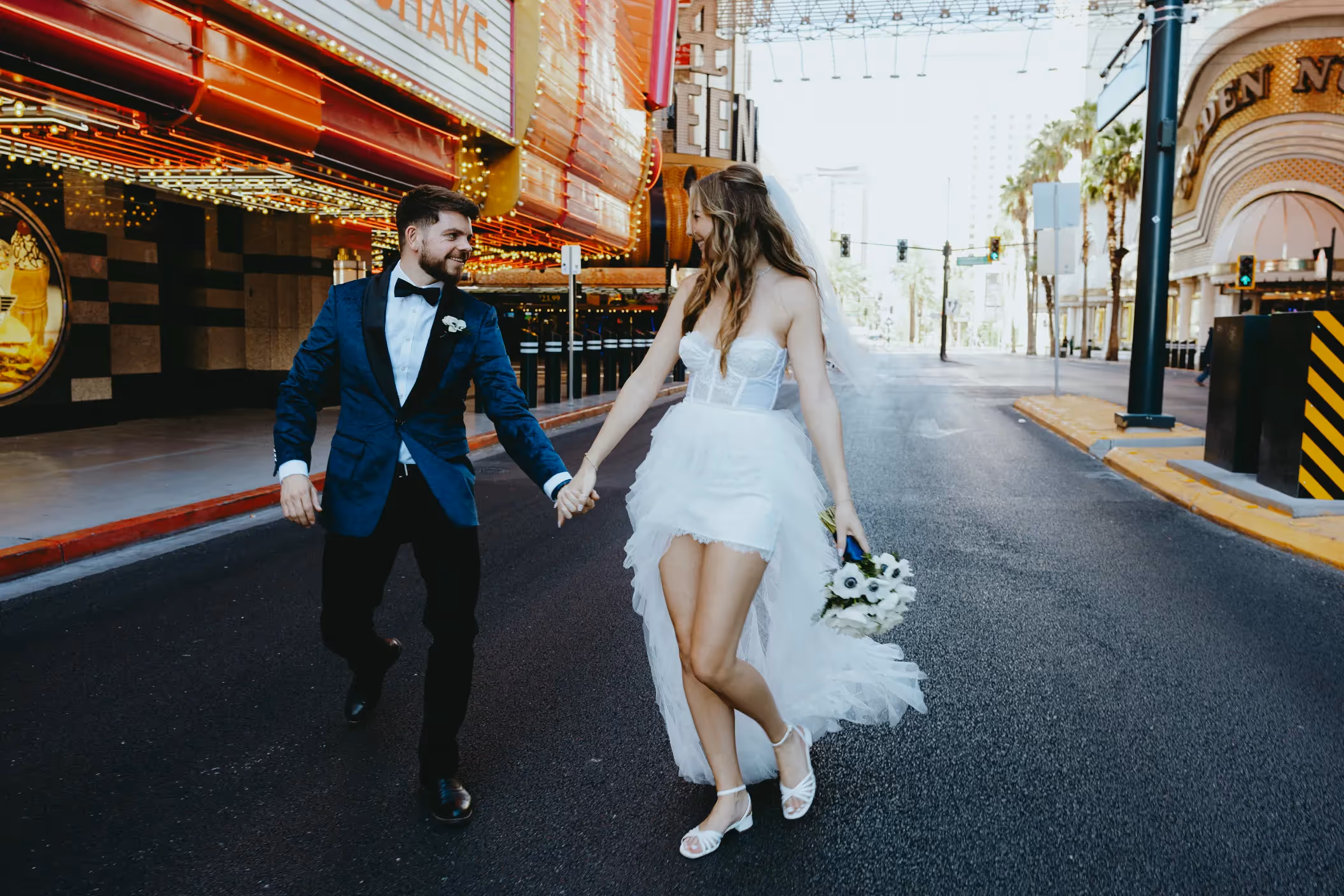 Gosia and Nathan's fun Downtown Las Vegas elopement, newlyweds holding hands and running down Fremont Street surrounded by neon lights
