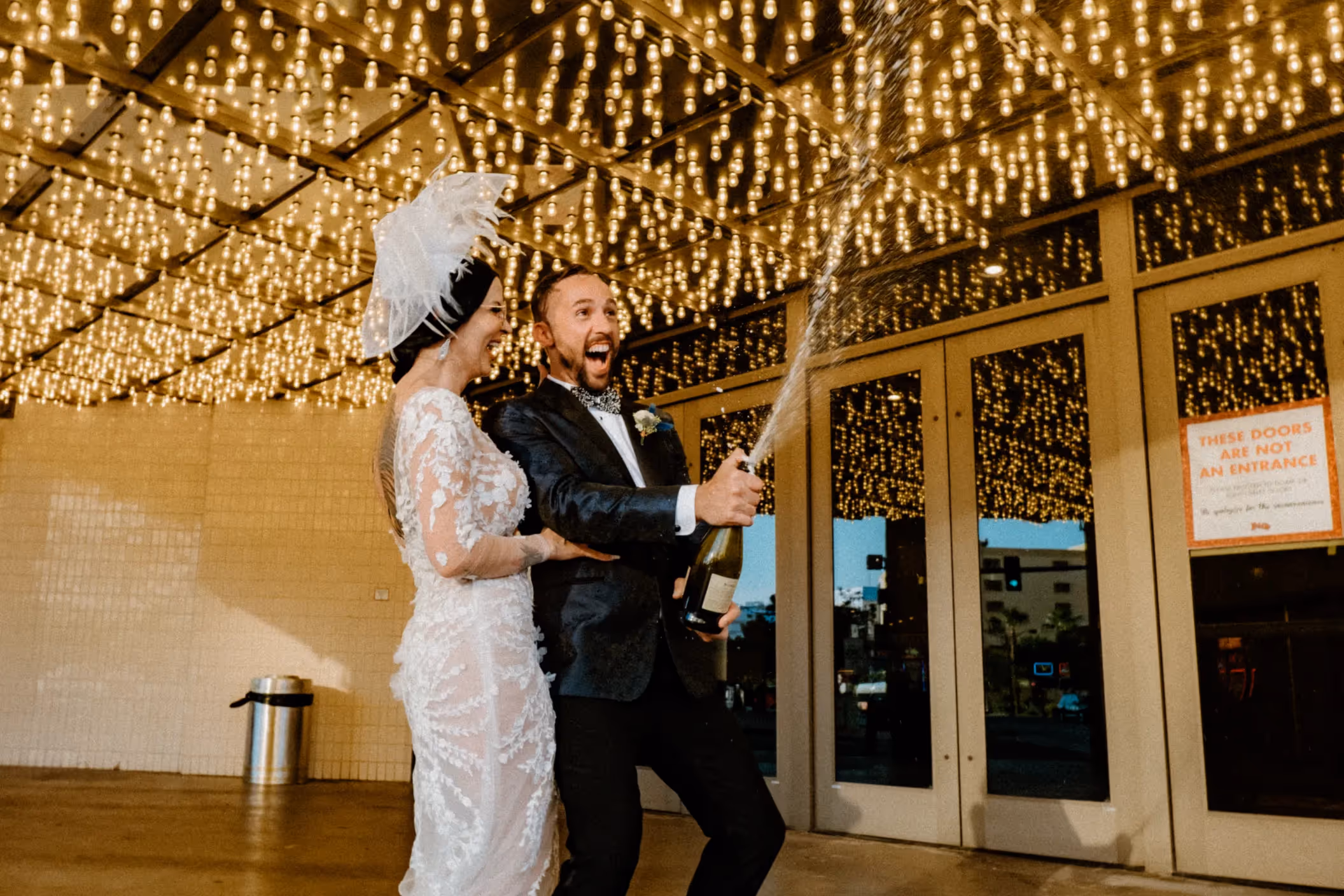 Olivia and Jon's celebratory Las Vegas wedding, couple popping champagne under glittering casino lights in Downtown