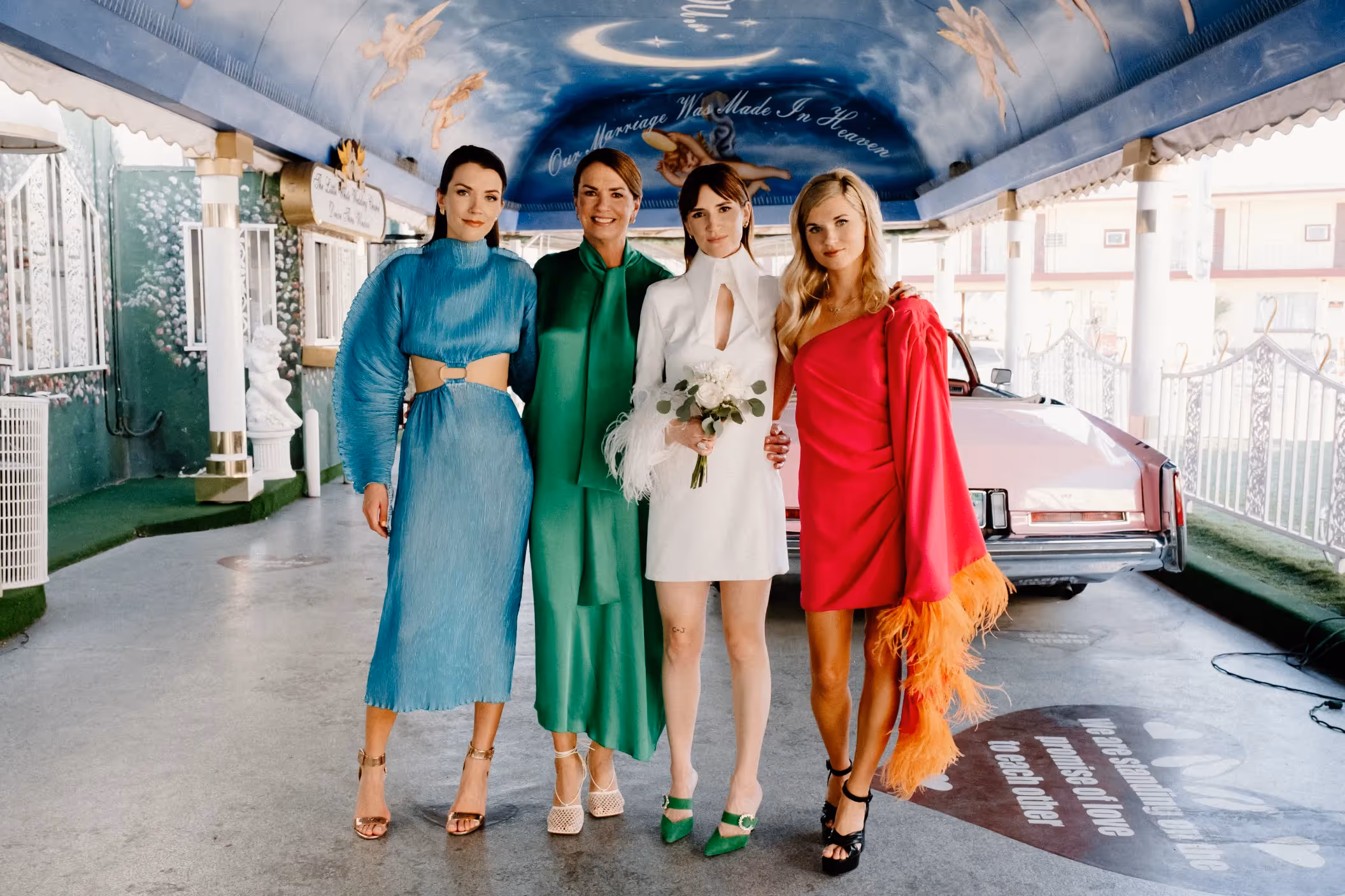 Claire and Oren's colorful Las Vegas chapel wedding, bride and bridesmaids in vibrant dresses posing in retro-themed "Tunnel of Love"