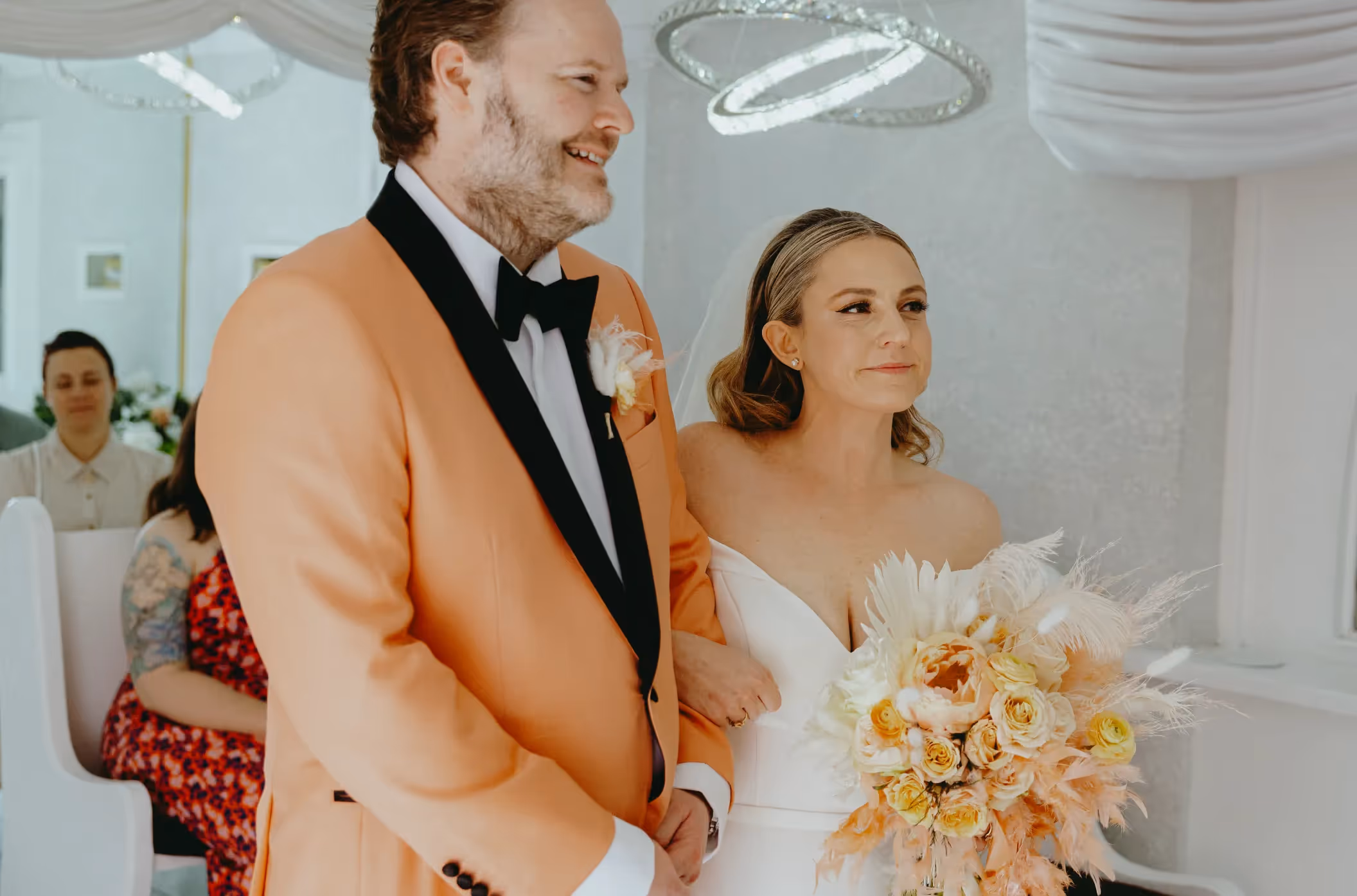 Ruth and Sean's stylish Downtown Las Vegas wedding, couple beaming during ceremony in chic chapel with groom in eye-catching peach tuxedo