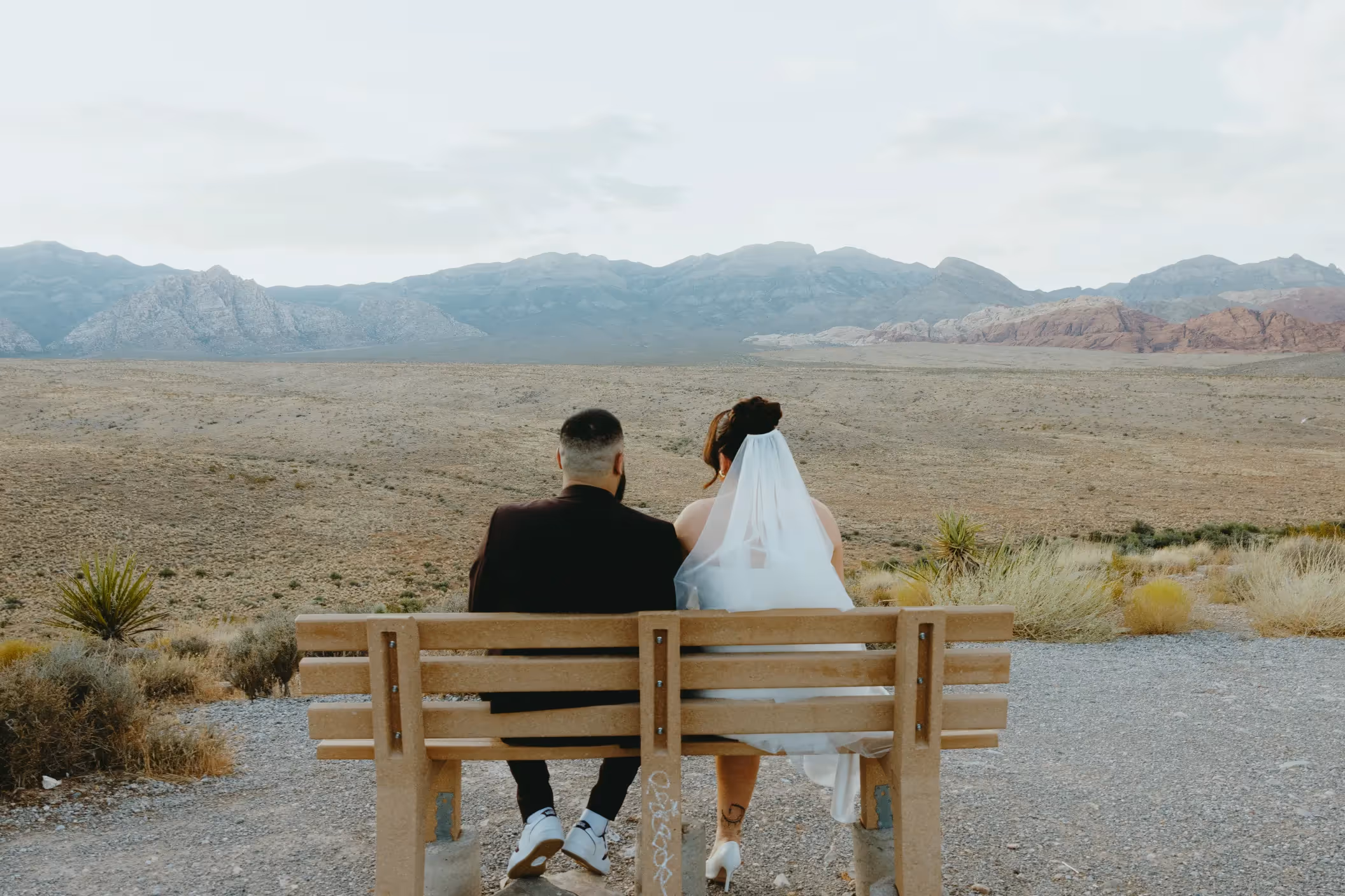 Red Rock Canyon elopement moment with Jessica and Jason overlooking vast desert landscape from wooden bench