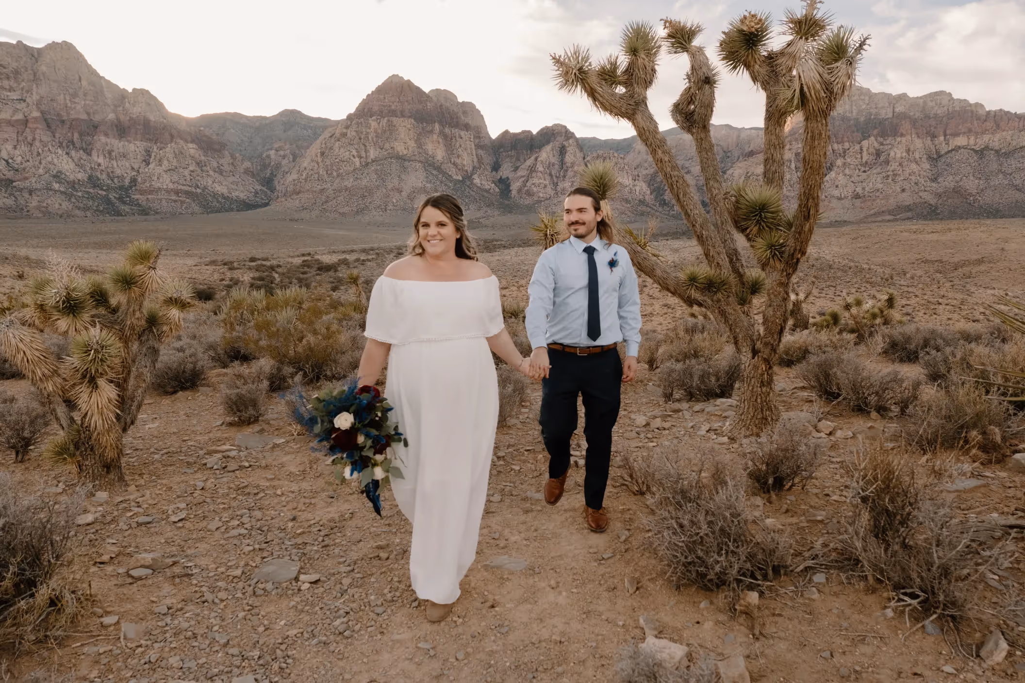 Christina and Aaron's rustic desert elopement at Red Rock Canyon, walking hand-in-hand among Joshua trees with majestic mountain views near Las Vegas