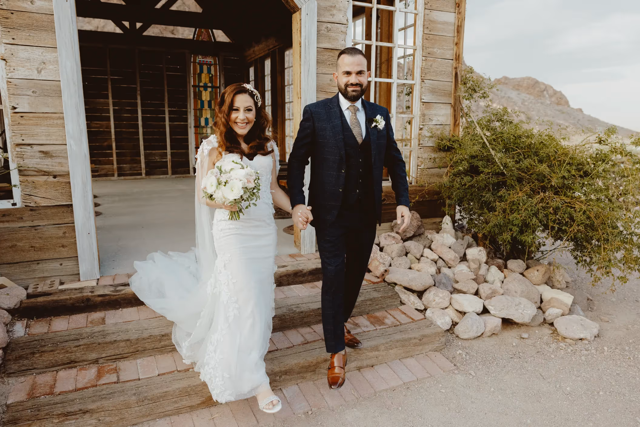Aysen and Erkut's charming Las Vegas area elopement at Nelson Ghost Town, couple exiting wooden chapel with mountain vista in background