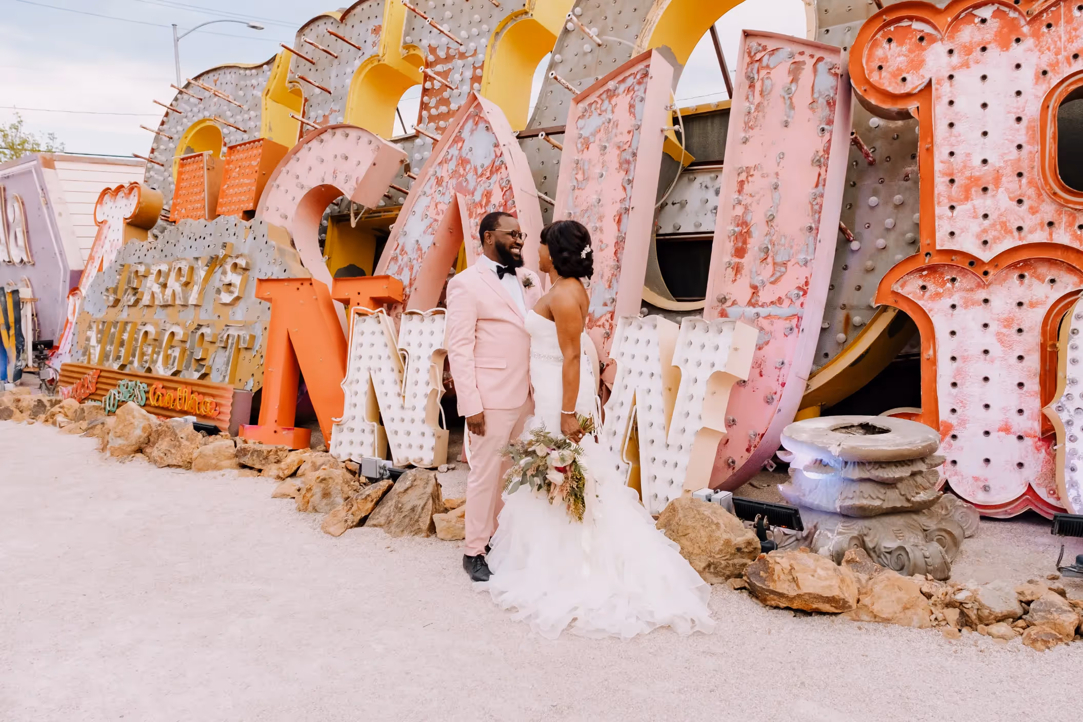 Celena and Darius' romantic Las Vegas elopement at the Neon Museum, posing in front of colorful vintage signs including "Jerry's Nugget" Casino