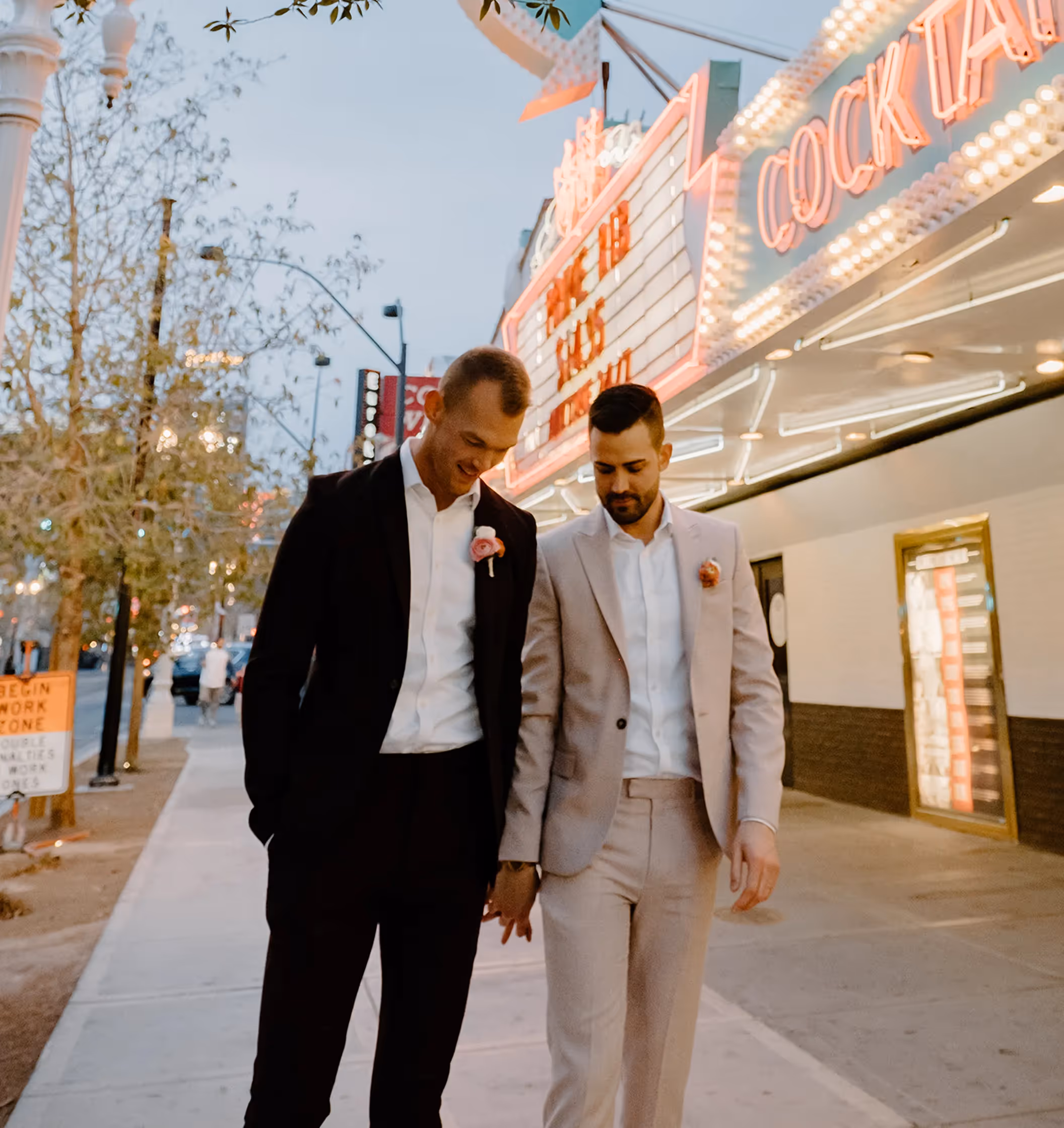 Jessica and Dave's unique Las Vegas wedding, couple strolling hand-in-hand past the vintage Vegas Vic sign on Fremont Street
