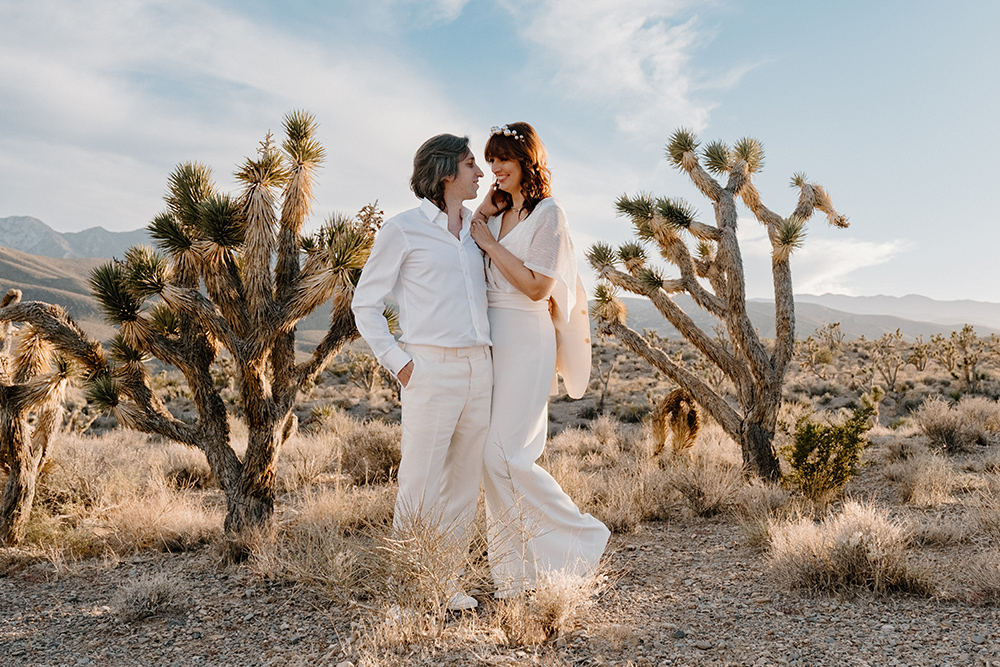 Las Vegas desert elopement of Re and Ras, couple in traditional Indian wedding attire walking hand-in-hand against backdrop of rugged mountains