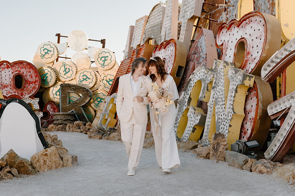 Nicolle and Ryan's vibrant Las Vegas elopement at the Neon Museum, posing in front of iconic 'Lady Lucky' sign and 'Hot' Casino neon letters