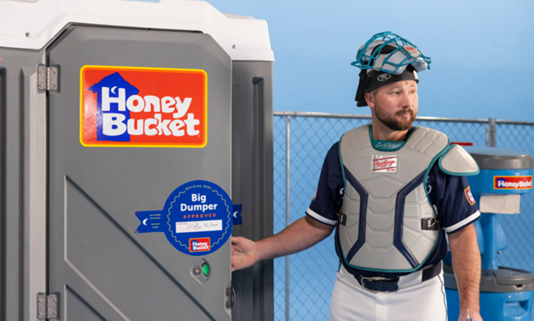 Seattle Mariners Catcher Cal Raleigh going into a Honey Bucket portable restroom