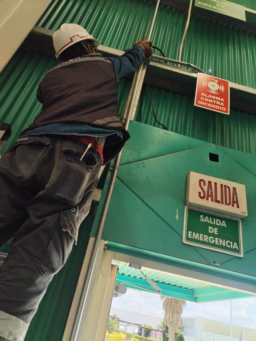 Un colaborador de ICISI sonriendo mientras instala un sistema contra incendios.