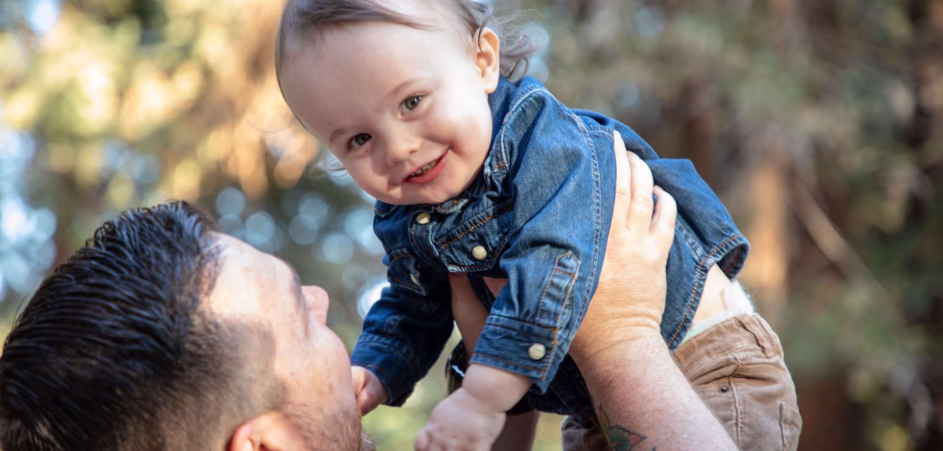 A man holding a smiling baby up in the air